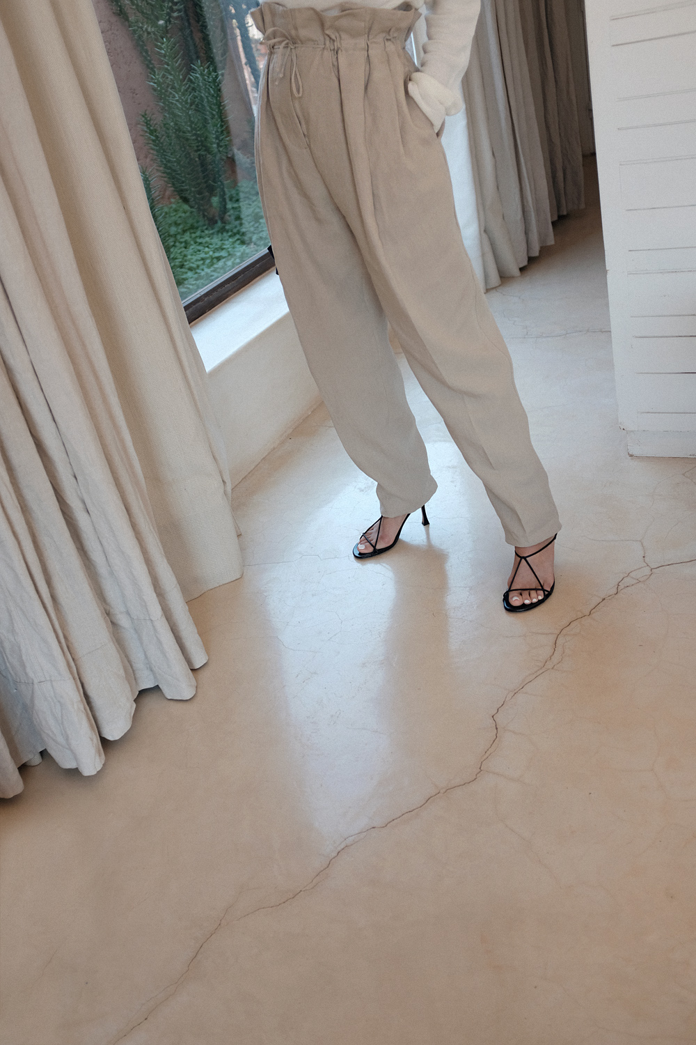 Nisi is wearing: Acne Studios Paperbag pants, Céline strap sandals, Wool crew neck shirt, The Row Ascot bag, Alighieri La Jetée earrings