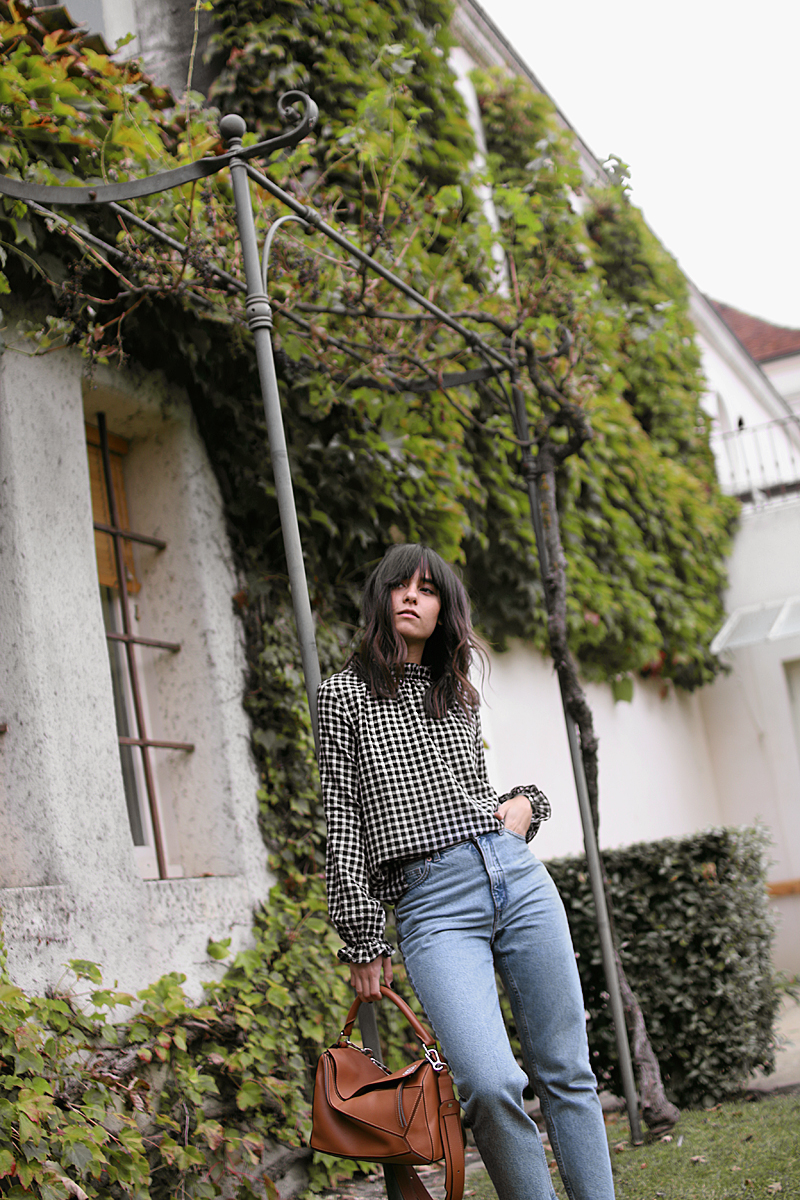 Nisi is wearing: Gingham pattern blouse, Gucci Princetown Slipper, Loewe Puzzle bag, mom jeans