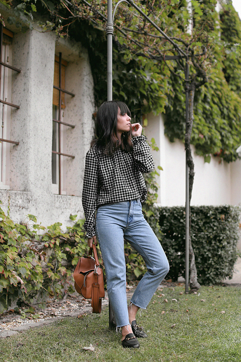 Nisi is wearing: Gingham pattern blouse, Gucci Princetown Slipper, Loewe Puzzle bag, mom jeans