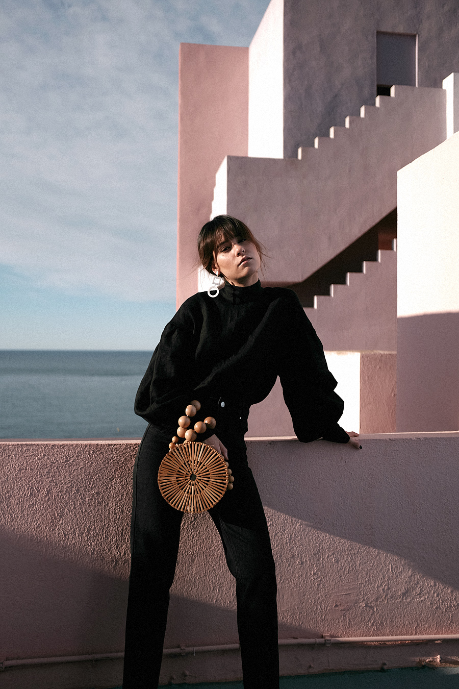 Outfit: Geometric Forms. Nisi is wearing: Cult Gaia Luna Bag, Manolo Blahnik Maysale Pumps, Mother-of-pearl earrings, Black mom jeans, Black high-neck blouse