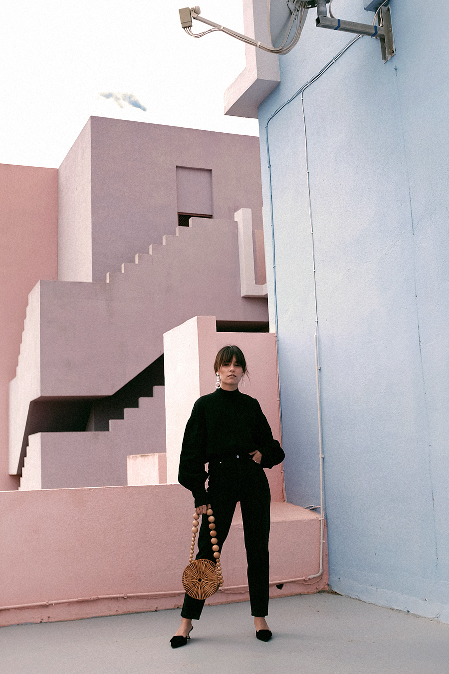 Outfit: Geometric Forms. Nisi is wearing: Cult Gaia Luna Bag, Manolo Blahnik Maysale Pumps, Mother-of-pearl earrings, Black mom jeans, Black high-neck blouse