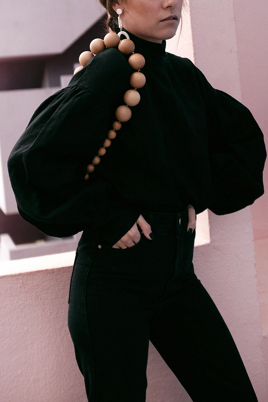 Outfit: Geometric Forms. Nisi is wearing: Cult Gaia Luna Bag, Manolo Blahnik Maysale Pumps, Mother-of-pearl earrings, Black mom jeans, Black high-neck blouse
