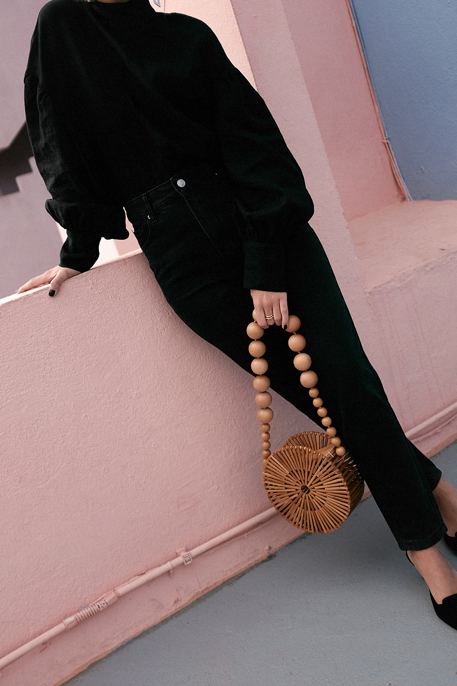 Outfit: Geometric Forms. Nisi is wearing: Cult Gaia Luna Bag, Manolo Blahnik Maysale Pumps, Mother-of-pearl earrings, Black mom jeans, Black high-neck blouse