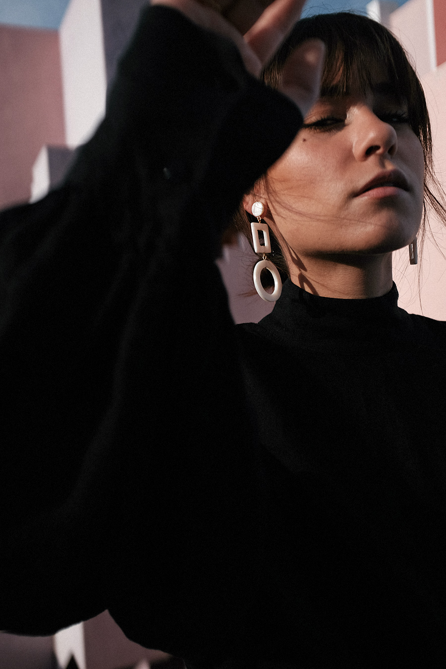 Outfit: Geometric Forms. Nisi is wearing: Cult Gaia Luna Bag, Manolo Blahnik Maysale Pumps, Mother-of-pearl earrings, Black mom jeans, Black high-neck blouse
