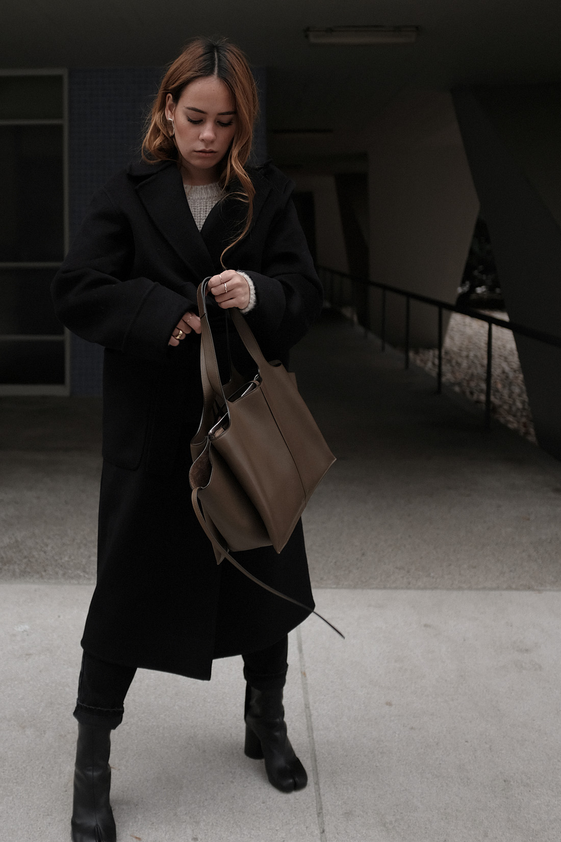 Desi is wearing: Maison Margiela Tabi boots, Céline Tri-Fold bag, Wrap coat, Knit jumper, Mom jeans L’Or Liquide maxi earrings by teetharejade