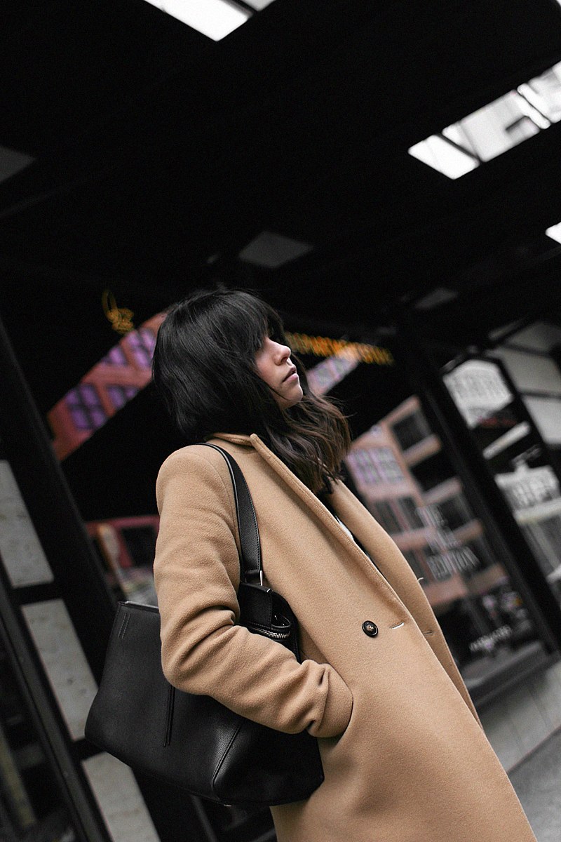 Nisi is wearing: Camel Coat, Céline Edge bag, skinny jeans, Jimmy Choo Tide sling-back pumps, V-neck knit