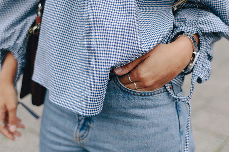 Desi is wearing: Gingham off-the-shoulder top, mom jeans, Hermès Oran sandals, Chloé Faye bag