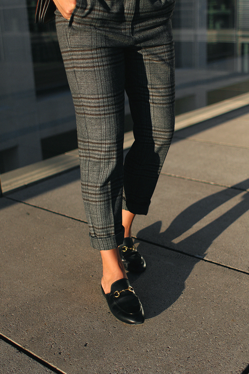 Desi is wearing: Mango checked trousers, Zara blouse, Gucci Princetown slippers, Chloé Faye bag.