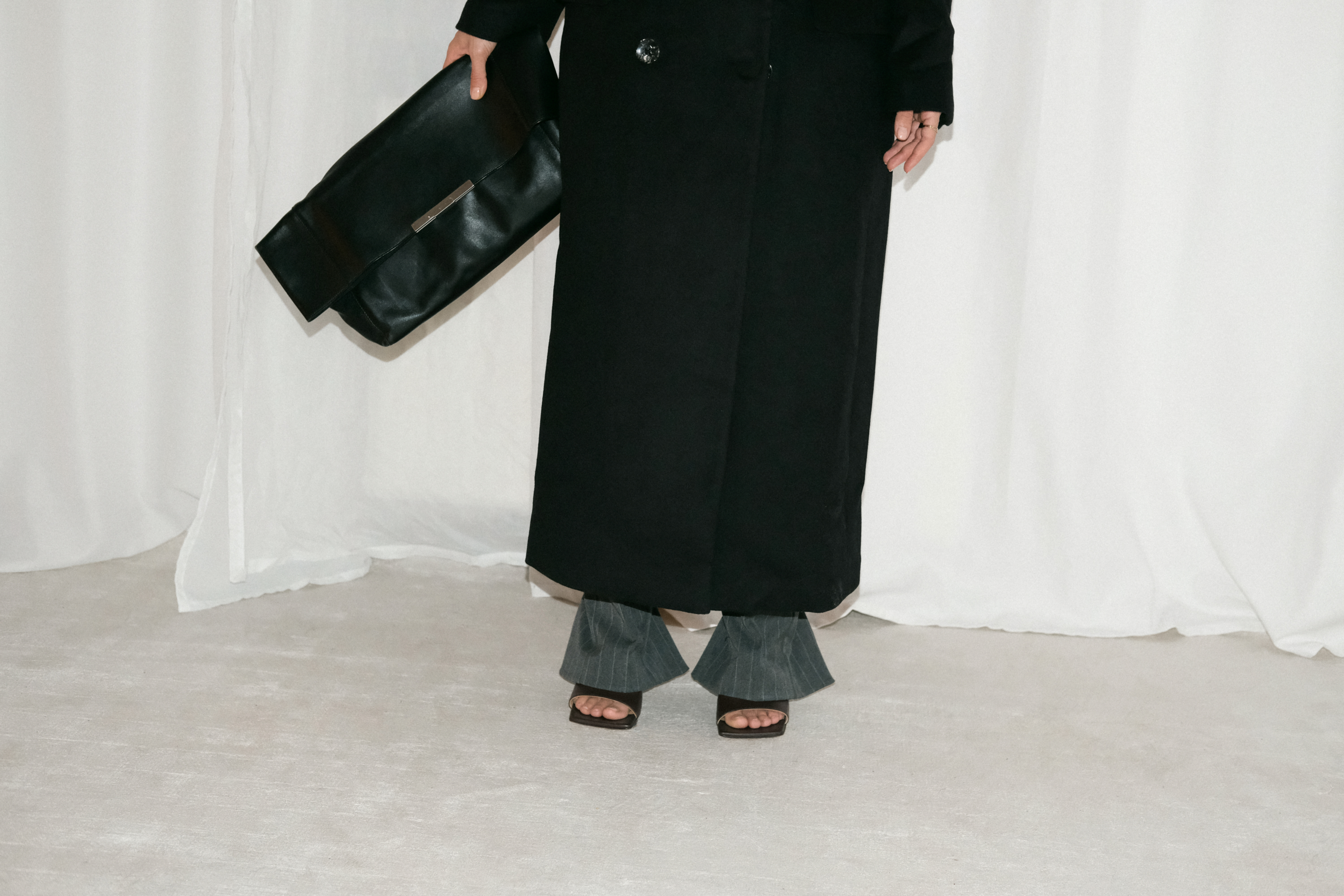 Desi wearing: Double breasted coat EDITED, Script-Logo sunglasses SAINT LAURENT, Silver hoops STILNEST, Pin-striped pants MANGO, Stretch mule sandals BOTTEGA VENETA, Big soft clutch CÉLINE, Silver watch KAPTEN & SON