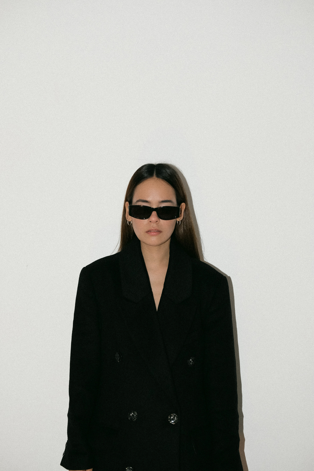 Desi wearing: Double breasted coat EDITED, Script-Logo sunglasses SAINT LAURENT, Silver hoops STILNEST, Pin-striped pants MANGO, Stretch mule sandals BOTTEGA VENETA, Big soft clutch CÉLINE, Silver watch KAPTEN & SON