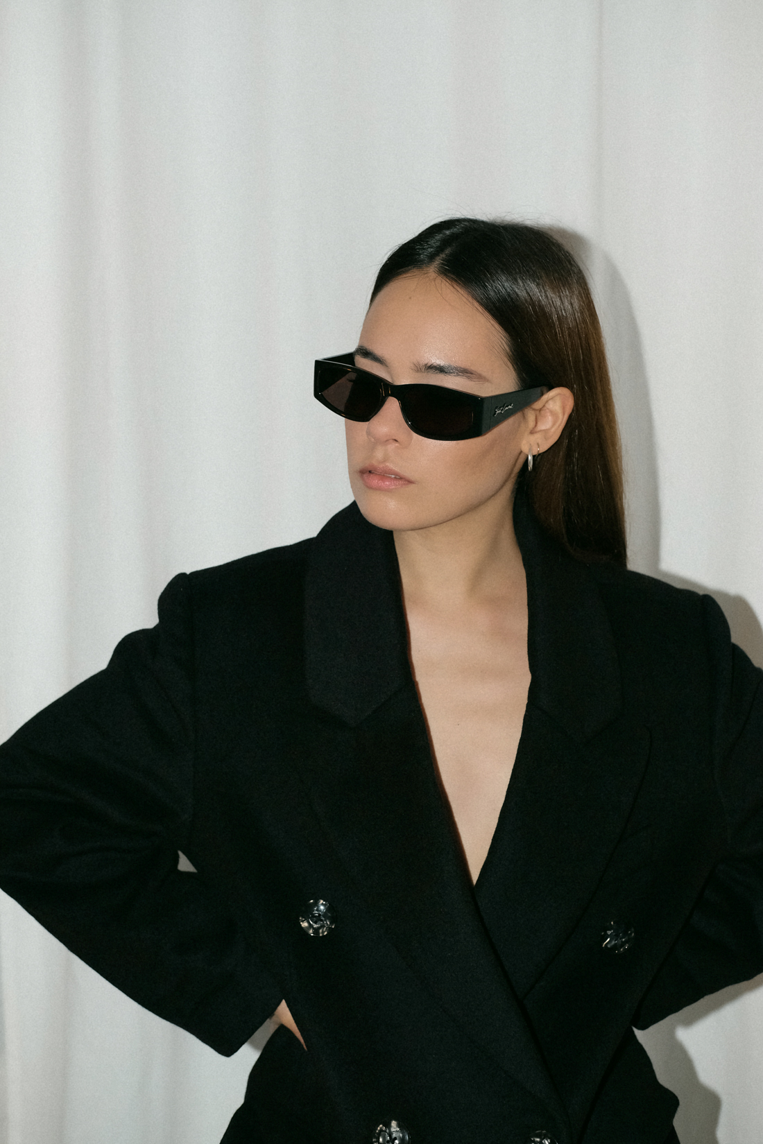 Desi wearing: Double breasted coat EDITED, Script-Logo sunglasses SAINT LAURENT, Silver hoops STILNEST, Pin-striped pants MANGO, Stretch mule sandals BOTTEGA VENETA, Big soft clutch CÉLINE, Silver watch KAPTEN & SON