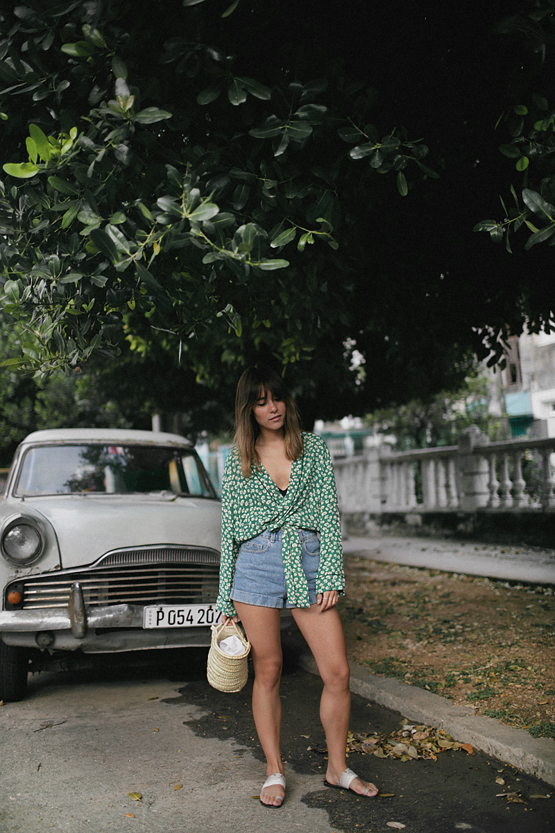 Nisi is wearing: Ganni Kimono, high-waisted denim shorts, straw bag, sandals, gold mesh watch