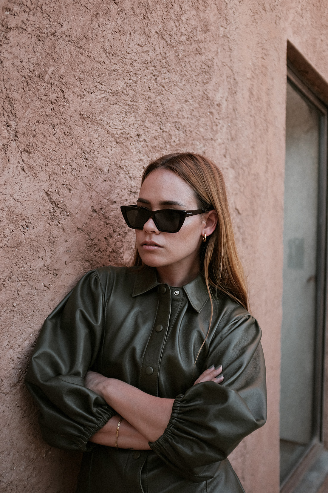 Desi is wearing: Ganni Leather minidress, Rejina Pyo Zeo Strappy leather mules, Saint Laurent New Wave 276 cat-eye sunglasses, Earrings L’Or Liquide