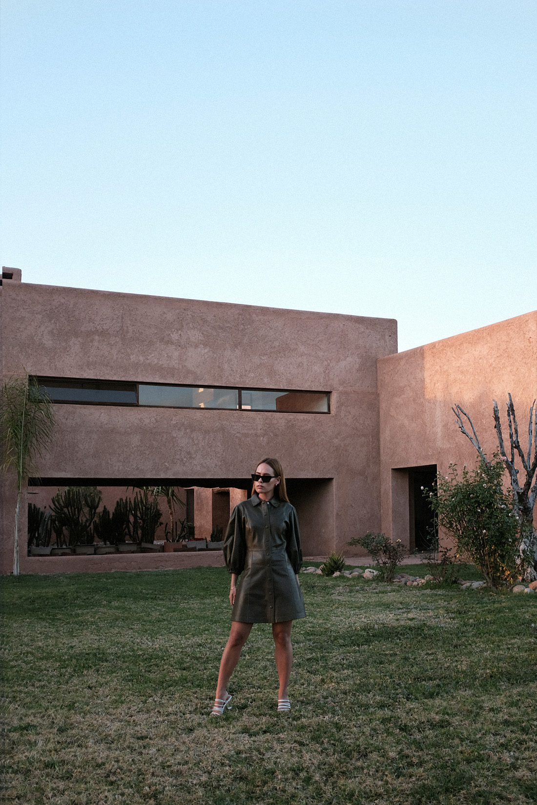 Desi is wearing: Ganni Leather minidress, Rejina Pyo Zeo Strappy leather mules, Saint Laurent New Wave 276 cat-eye sunglasses, Earrings L’Or Liquide