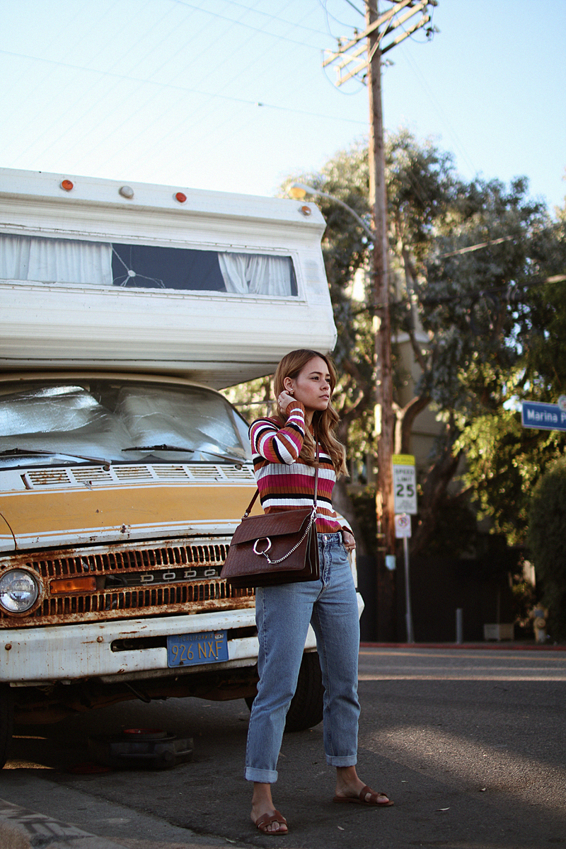 Outfit: Multicolored Stripes. Inspired by Stranger Things. Desi is wearing a multicolored striped shirt, mom jeans, Hermes Oran sandals and Chloé Faye bag.