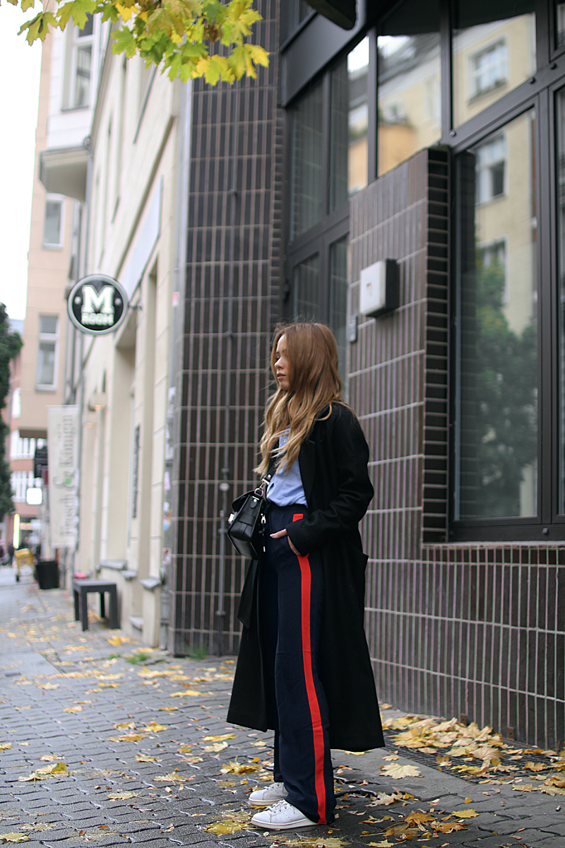 Desi is wearing: Proenza Schouler PS11 bag, side stripe pants, button down shirt, oversized coat and Adidas stan smith sneakers