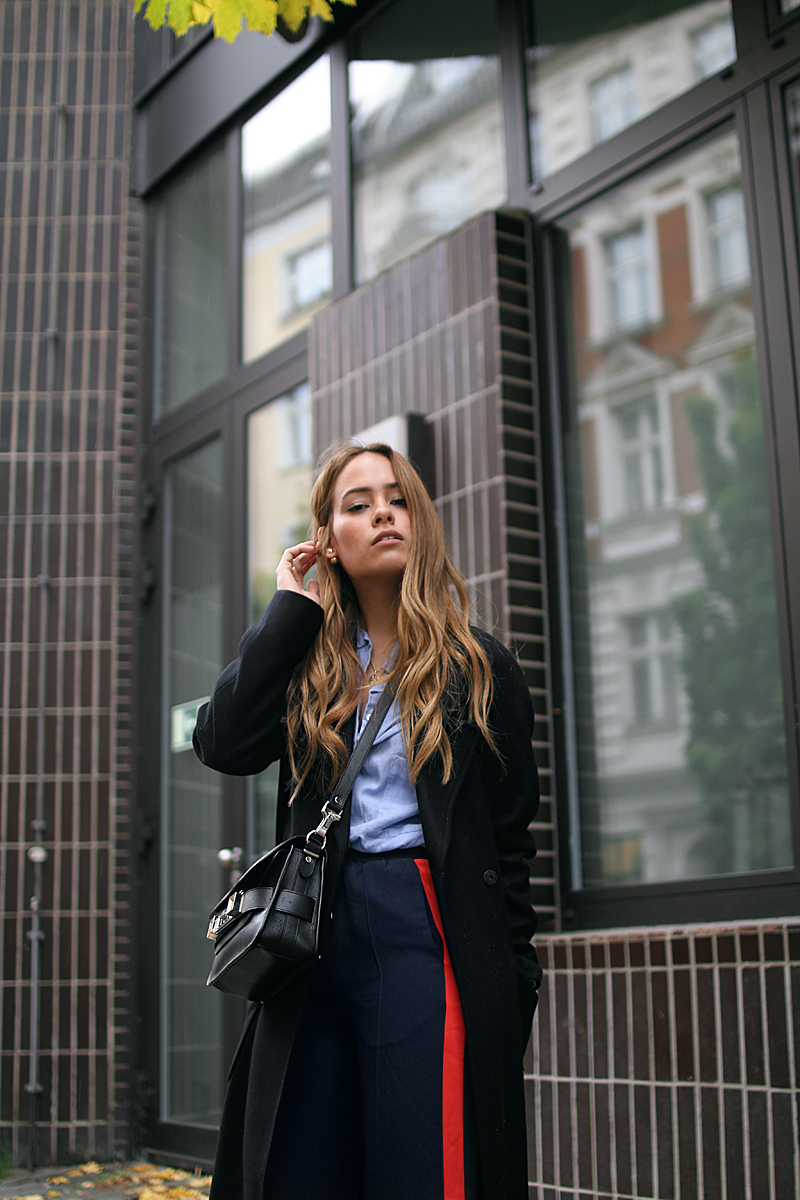 Desi is wearing: Proenza Schouler PS11 bag, side stripe pants, button down shirt, oversized coat and Adidas stan smith sneakers
