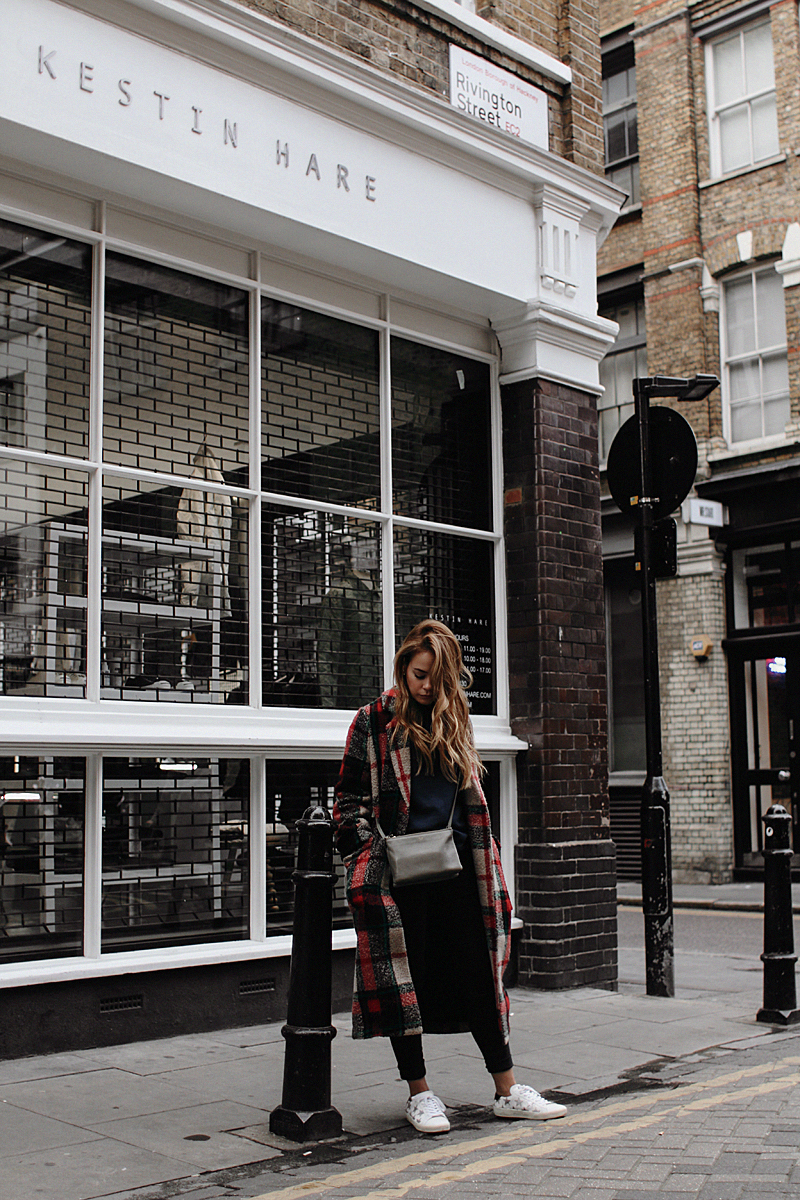 Desi is wearing: Céline Trio bag, print sweater, plaid coat, skinny jeans, Saint Laurent sneakers