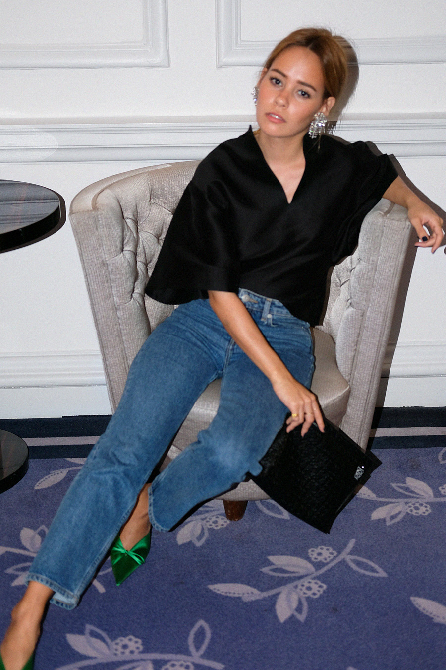 Desi is wearing: Balenciaga Knife mules, Totême Azurro top, Loewe T Pouch, denim jeans, Rhinestones earrings