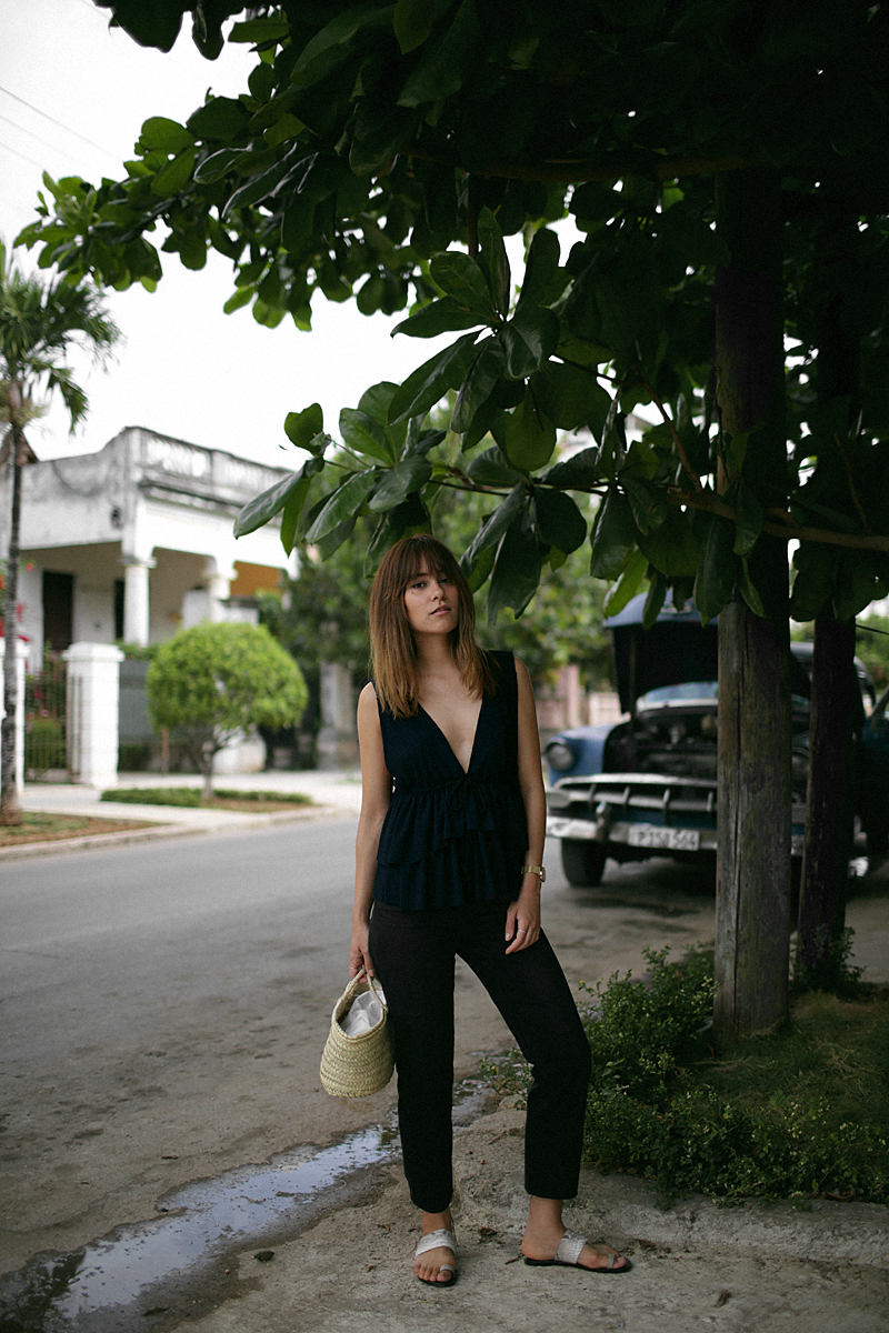 Nisi is wearing: See by Chloé top with ruffles, black denim mom jeans, ATP Atelier sandals, Straw bag, Rosefield gold mesh watch