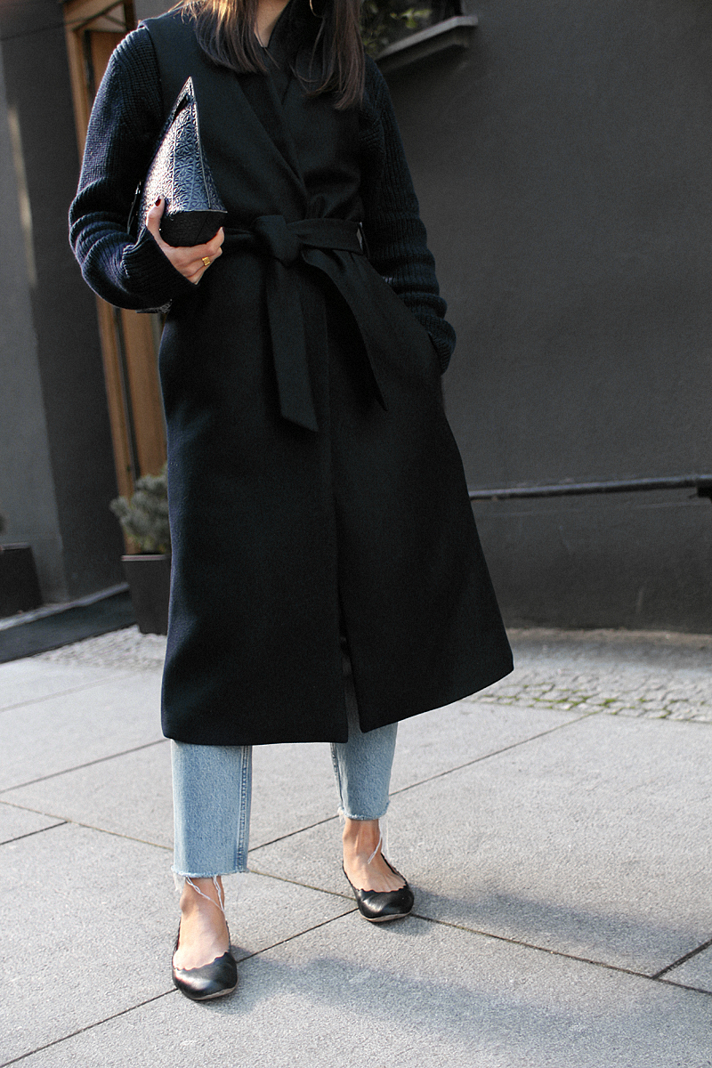 Nisi is wearing: Loewe T Pouch, Chloé Laurent ballet flats, wool vest, knit sweater, denim mom Jeans, statement earrings