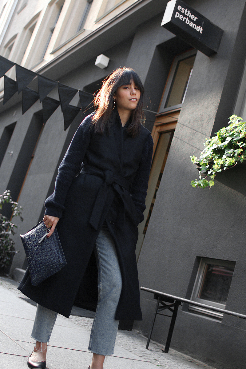 Nisi is wearing: Loewe T Pouch, Chloé Laurent ballet flats, wool vest, knit sweater, denim mom Jeans, statement earrings