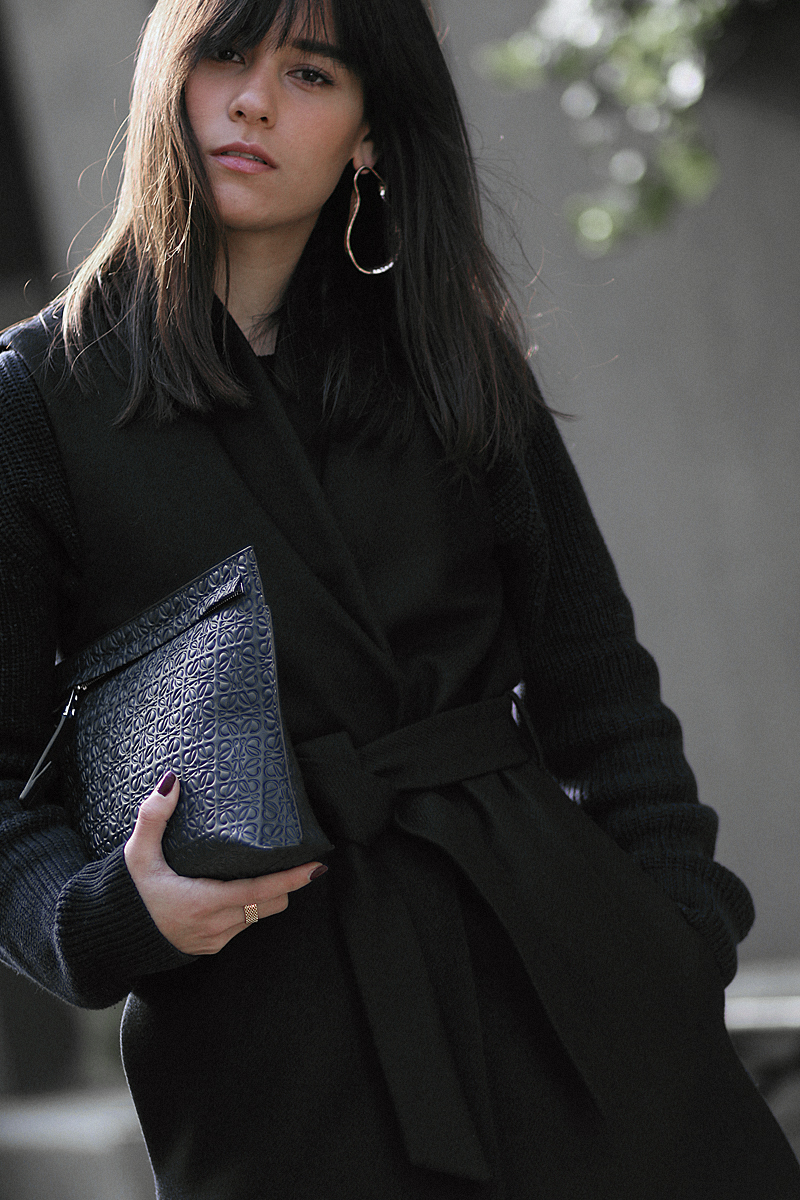 Nisi is wearing: Loewe T Pouch, Chloé Laurent ballet flats, wool vest, knit sweater, denim mom Jeans, statement earrings