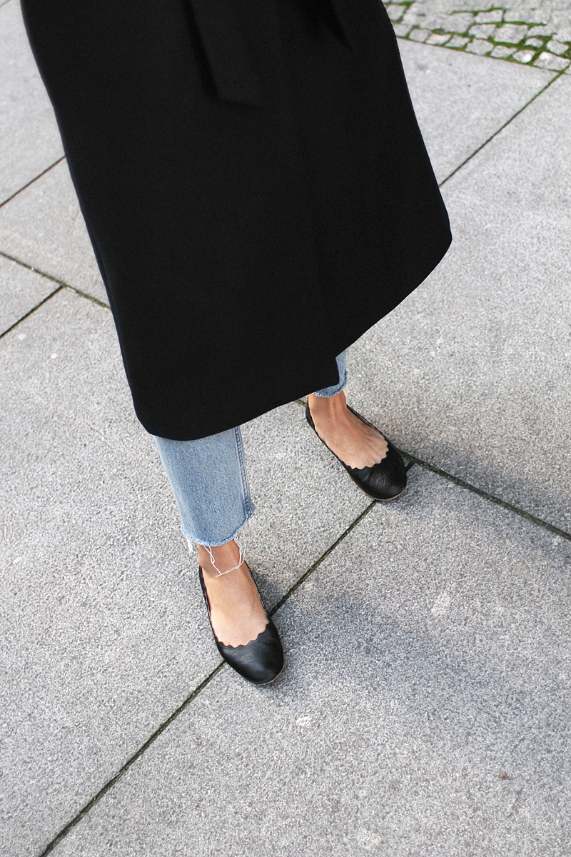 Nisi is wearing: Loewe T Pouch, Chloé Laurent ballet flats, wool vest, knit sweater, denim mom Jeans, statement earrings