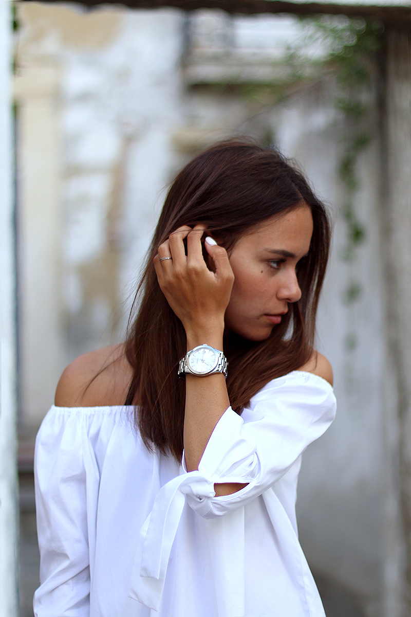 Nisi is wearing an off the shoulder top, highwaisted denim shorts, sparkly sandals and a Givenchy Bag in Lisbon